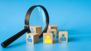 Egy nagyító és alakzatokkal jelzett fakockák, amik reprezentálják a témát, ami az idő- és költséghatékony toborzás.