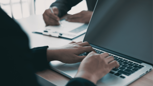 Két ember közösen dolgozik, egyikük laptopon gépel, a másik papíron jegyzetel – a jelenet jól szemlélteti, hogyan segíti az ATS rendszer a toborzási folyamatok digitalizálását és átláthatóságát.