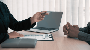 Két ember beszélget egy irodában laptop mellett, a kép a felnőtt kölcsönzés most diák áron témát szemlélteti.