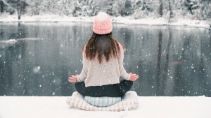 Egy diák nyugodtan meditál és pihen a havas tóparton a téli szünet alatt, szimbolizálva a munka és a feltöltődés egyensúlyát.