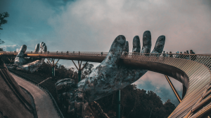 Szimbolikus kép a generációk közötti hídról: a vietnámi Arany Hidat (Cầu Vàng) tartó óriás kőkezek, melyen Z generációs diákok és más látogatók sétálnak át.